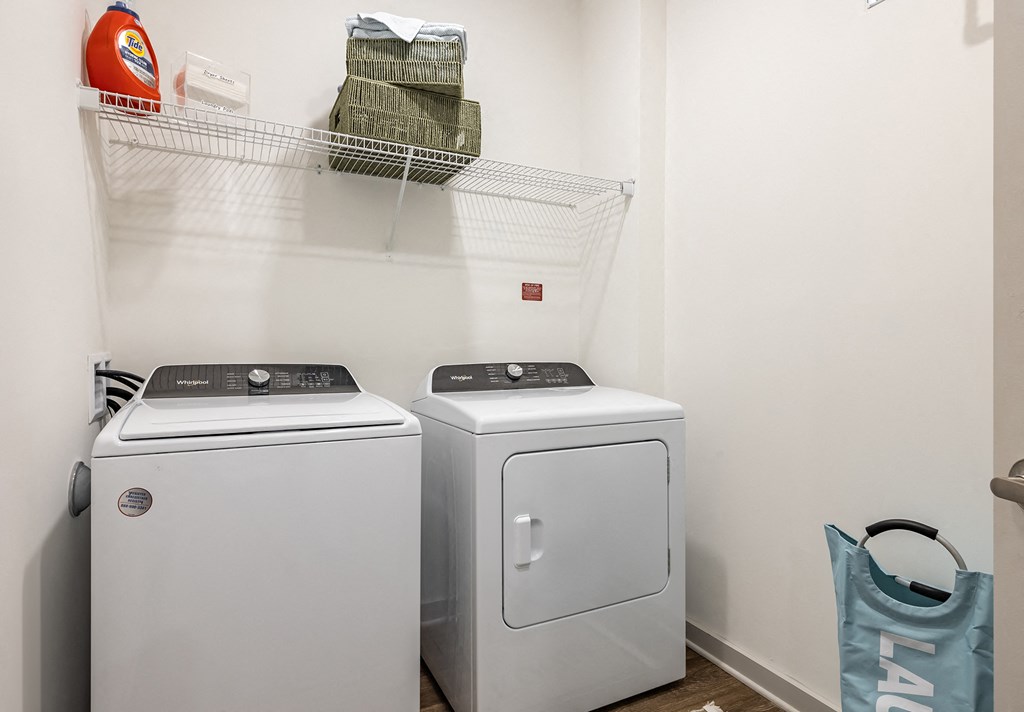 a washer and dryer in a laundry room with a shelf on the wall