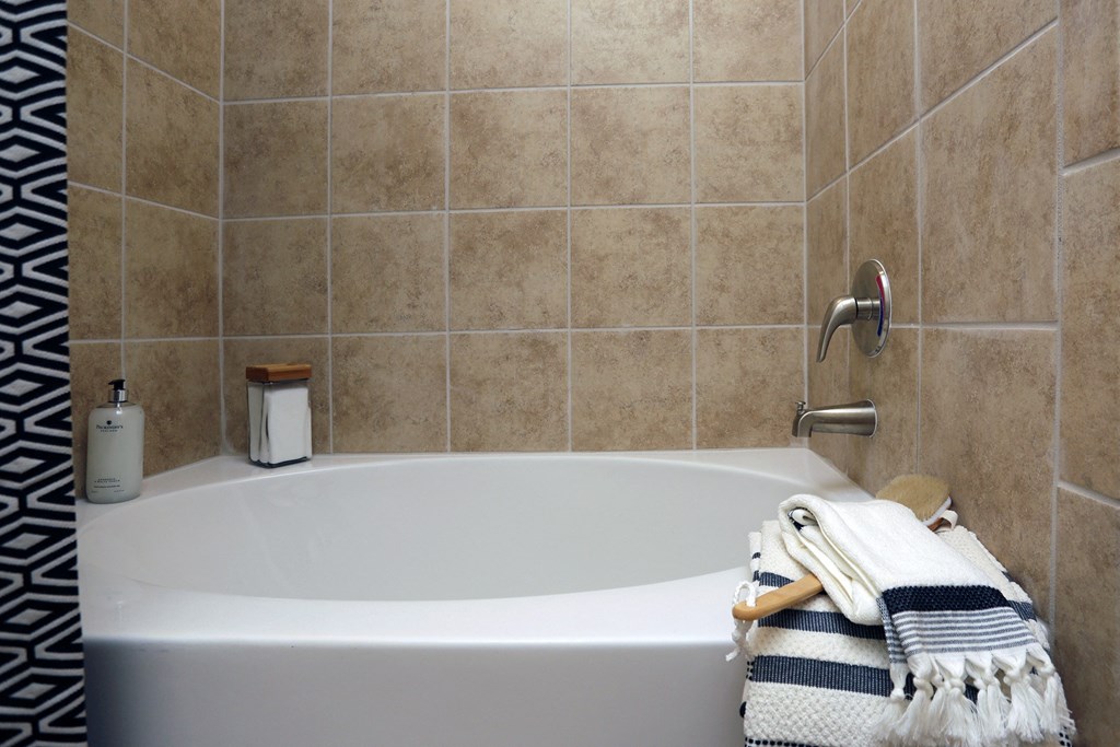 a white bath tub in a tiled bathroom