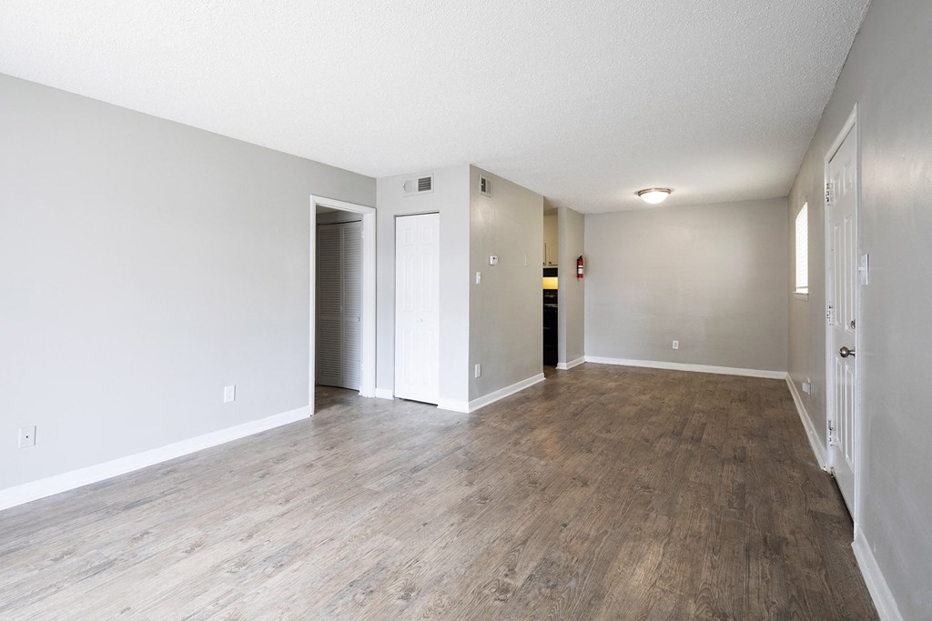 the living room and dining room of an apartment with wood flooring
