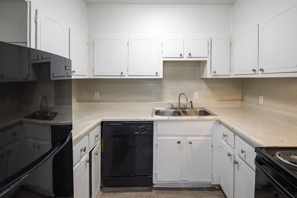 an empty kitchen with white cabinets and black appliances