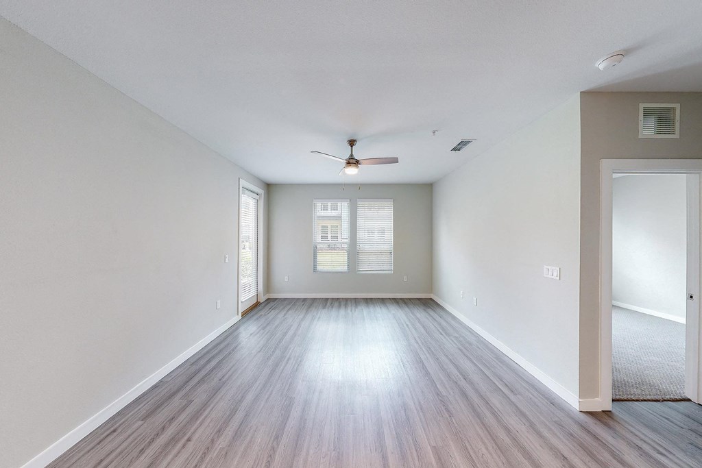 an empty living room with white walls and a ceiling fan