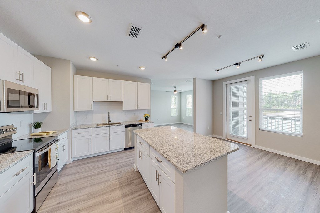 an open kitchen with white cabinets and a marble counter top