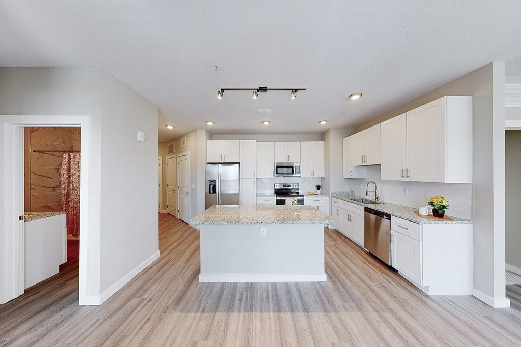an open kitchen with white cabinets and a marble counter top