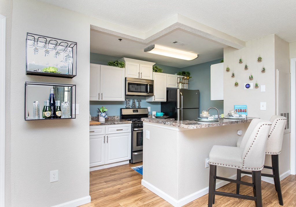an open kitchen and dining area with white cabinets and stainless steel appliances