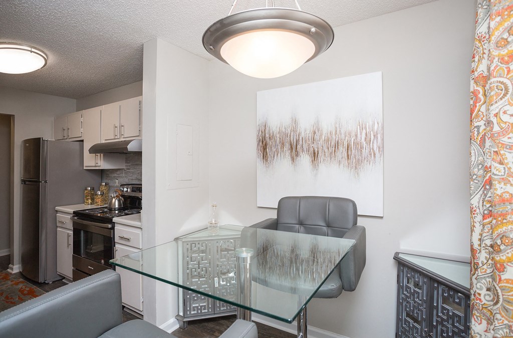 a dining room with a glass table and chairs and a kitchen