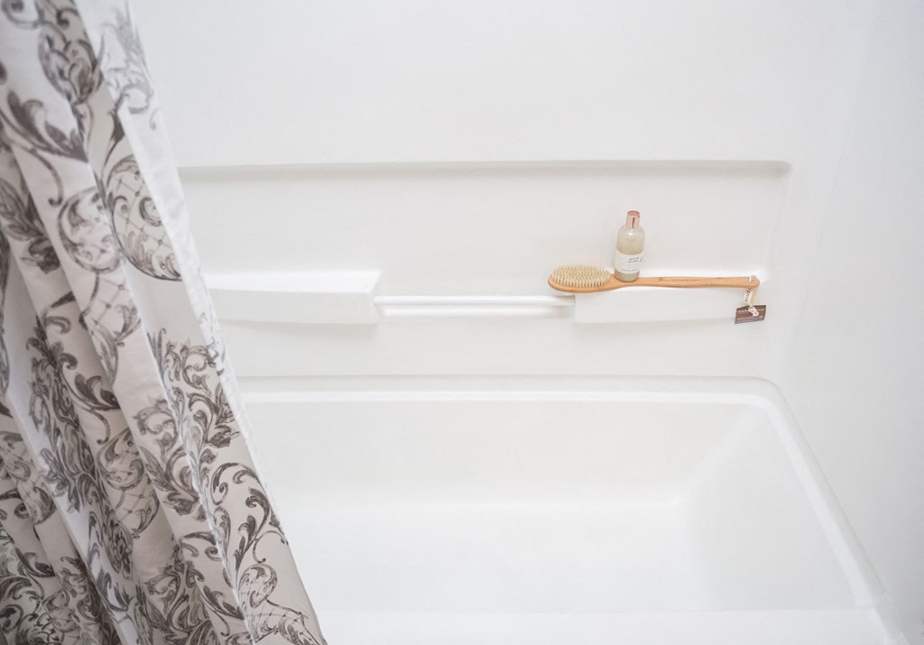 a white bathtub with a shower curtain and a soap dispenser on the shelf