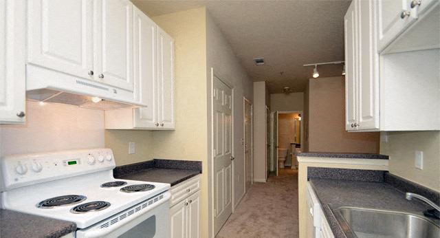 a long hallway with white cabinets and black and white floors