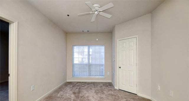 an empty bedroom with a ceiling fan and a window