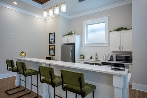 a kitchen with a bar and green chairs