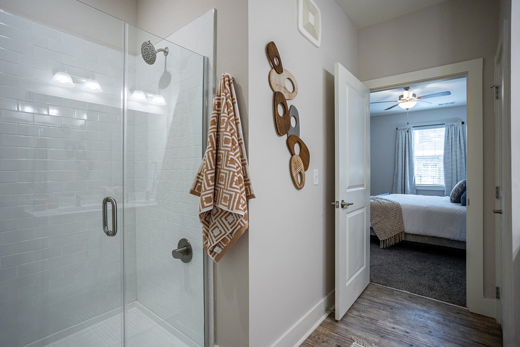 a bathroom with a glass shower and a door to a bedroom