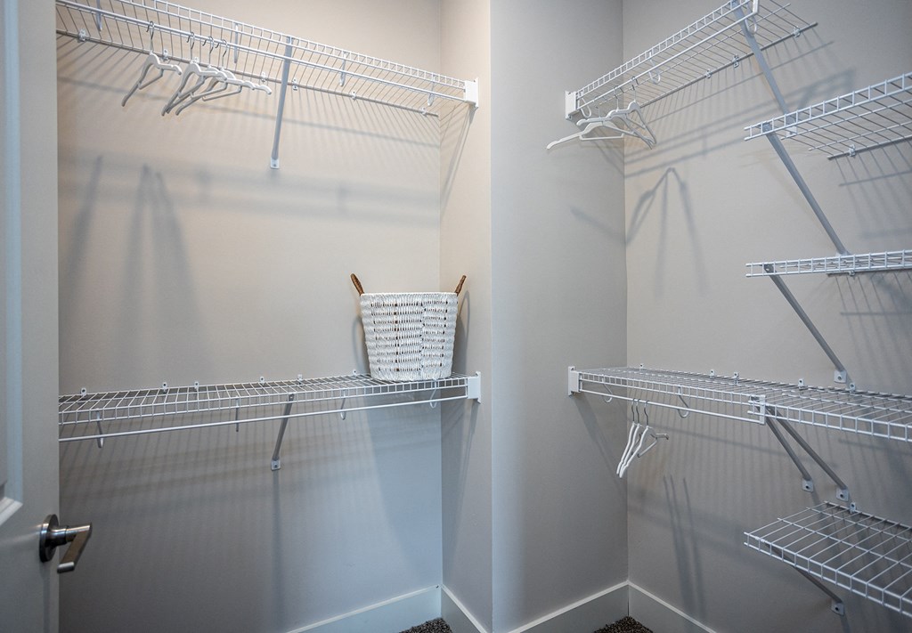 a walk in closet with empty shelves and a basket in the closet