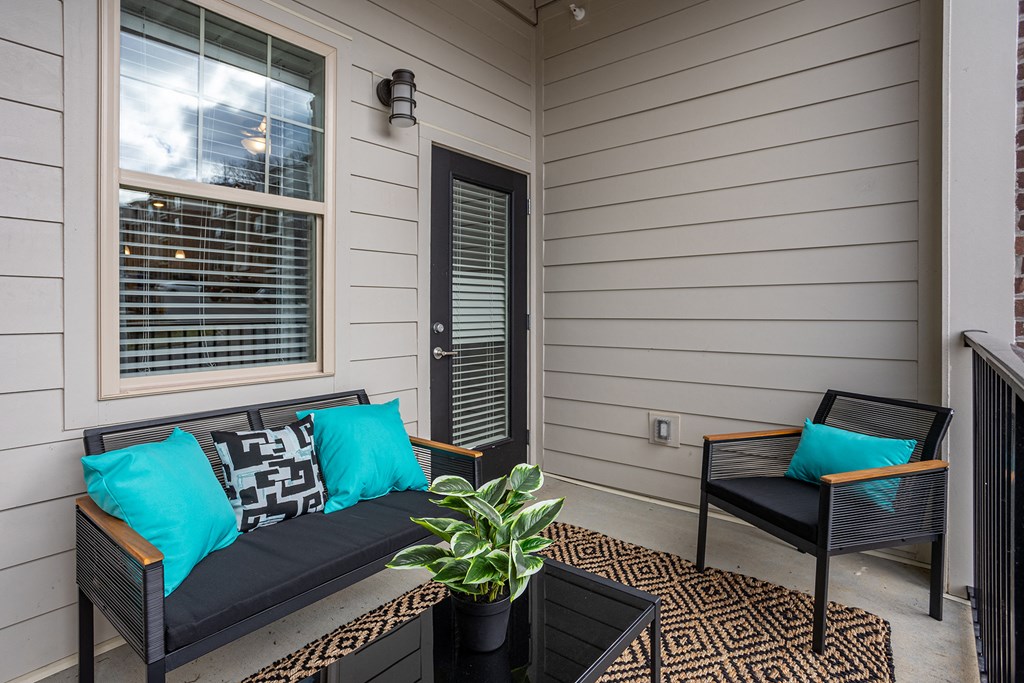 a small porch with a couch and chairs and a potted plant