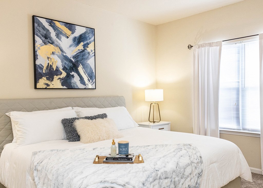 a bedroom with a white bed and a painting on the wall