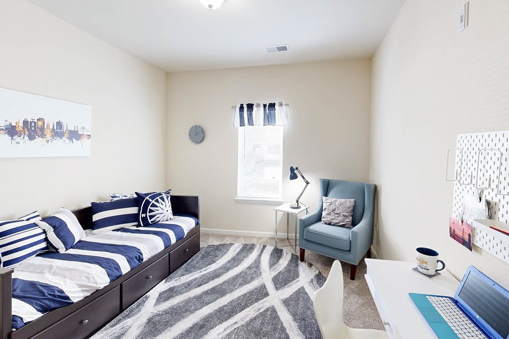 a bedroom with a bed and a desk with a laptop