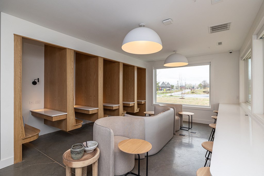 a lounge area with tables and chairs and a large window