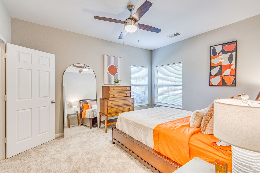 a bedroom with a bed and a ceiling fan and a mirror