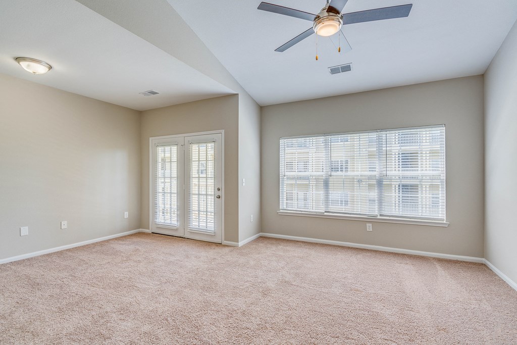 an empty living room with a ceiling fan and a window