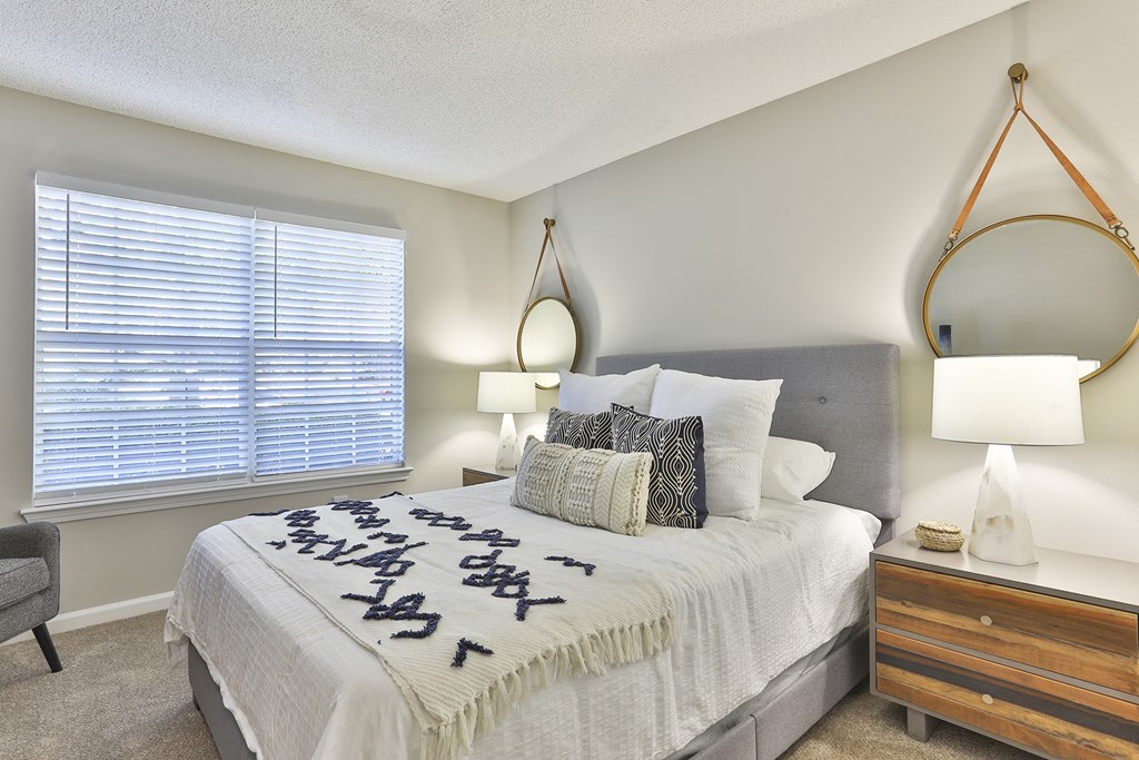 a bedroom with a large window and a large bed with a white comforter and pill  at Crestmont at Thornblade, Greenville