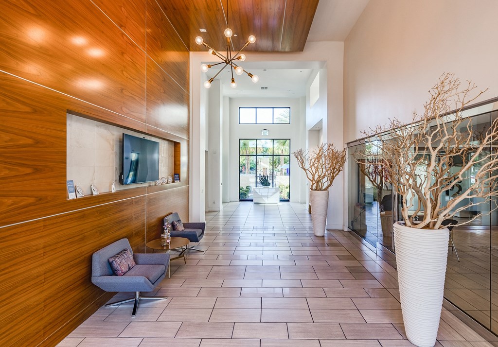 the lobby of a condo building with a lobby area with chairs and a tv