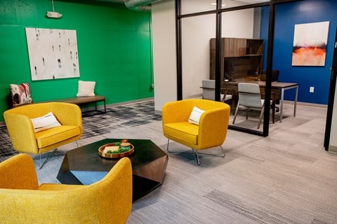 a living room with yellow chairs and a green wall and a table