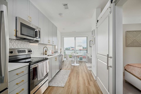 A kitchen with white cabinets and a wooden floor.