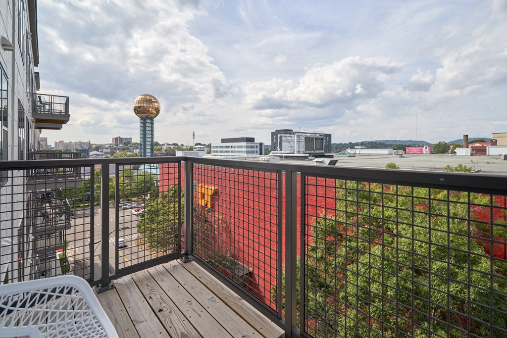 a balcony with a wooden deck and a fence and a city in the background
