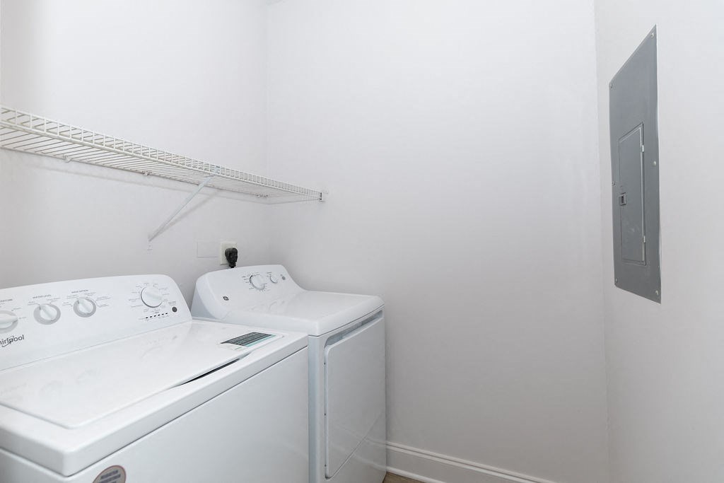 a white washer and dryer in a white laundry room with a shelf above