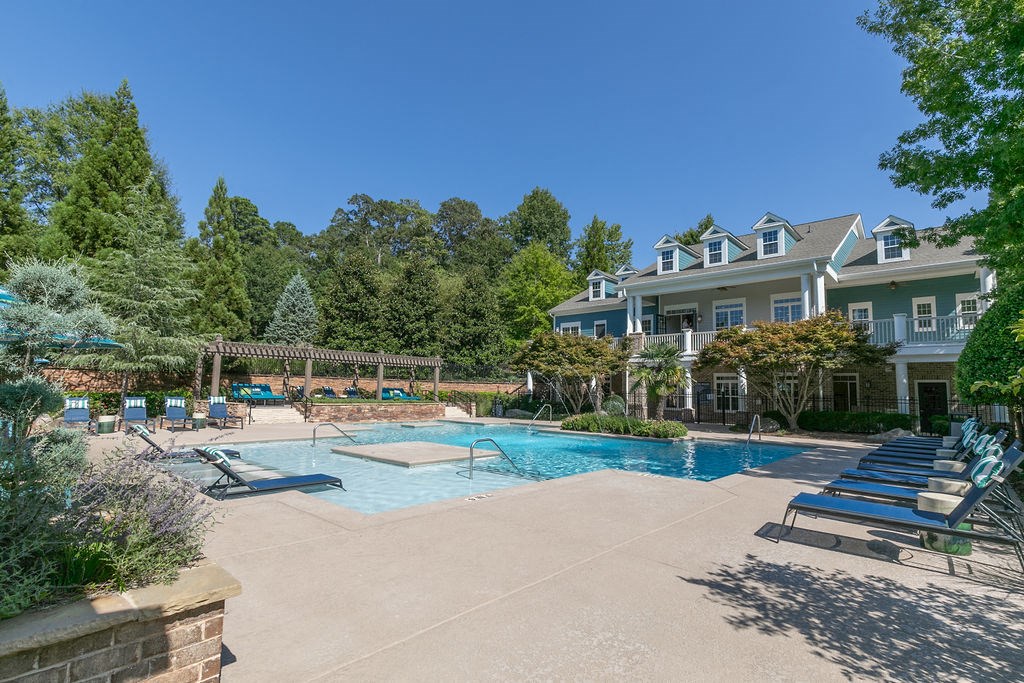 a swimming pool with chairs and a house in the background