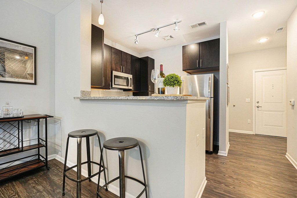 A kitchen with a white counter and black bar stools.