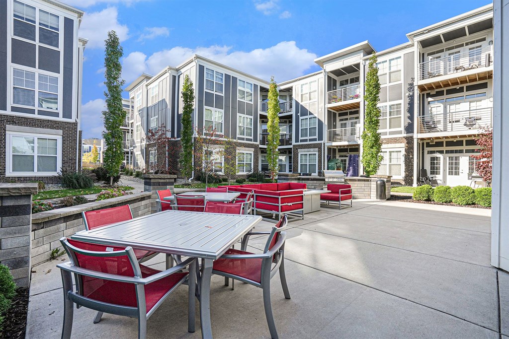 A patio with a table and chairs is surrounded by apartment buildings.