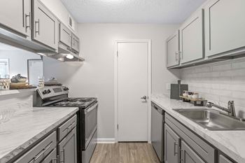 A kitchen with a white door and a stove top oven.