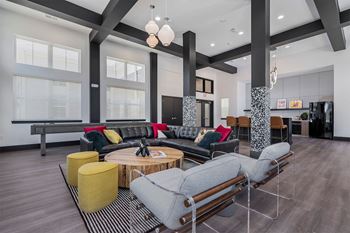 A modern living room with a grey sofa, yellow ottoman, and a coffee table.