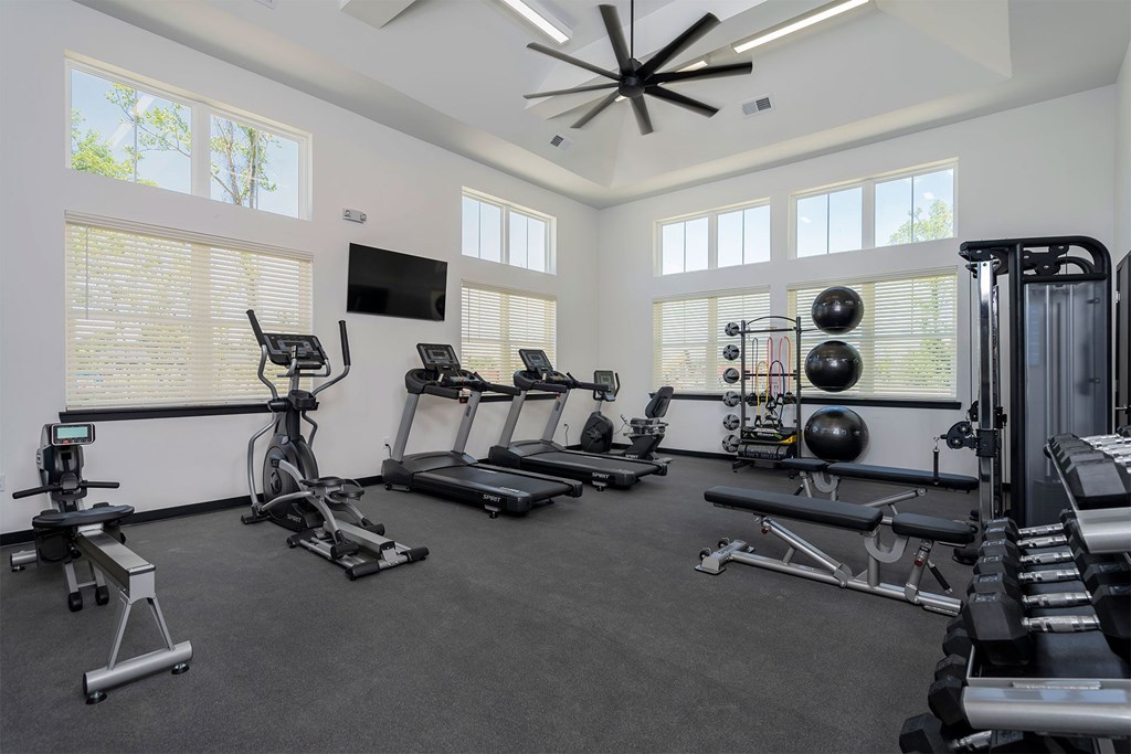 A spacious home gym with a variety of exercise equipment and a ceiling fan.