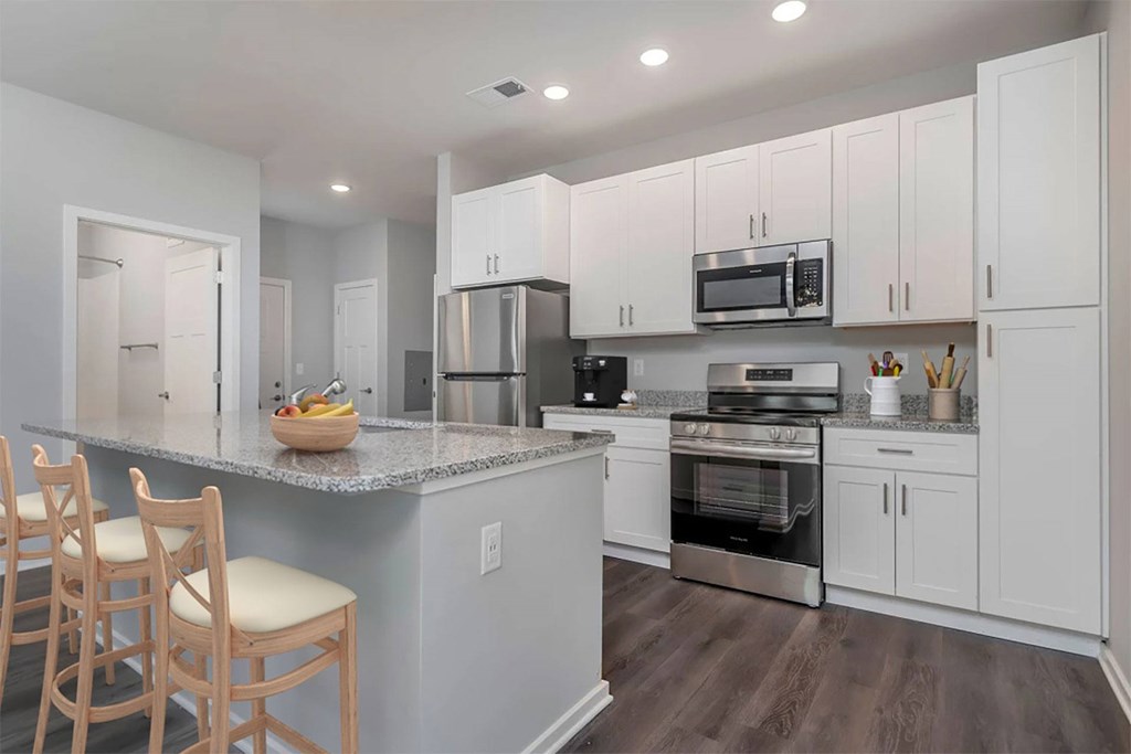A kitchen with white cabinets and a granite countertop.