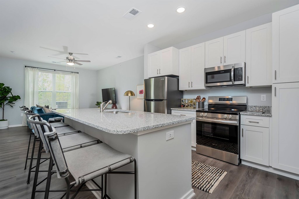 A kitchen with white cabinets and a marble countertop.