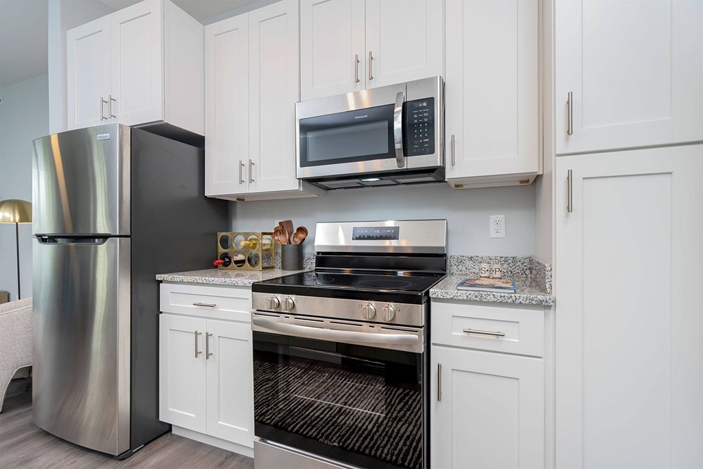 A modern kitchen with a stainless steel refrigerator, microwave, oven, and cabinets.