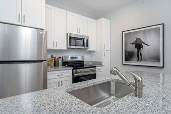 A modern kitchen with granite countertops and stainless steel appliances.