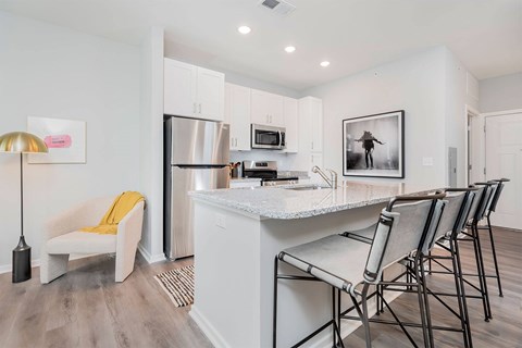 A kitchen with white cabinets and a white island with a black and white photo on the wall.