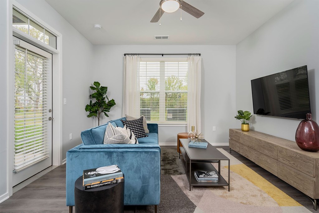 A living room with a blue couch, a coffee table, and a flat screen TV.
