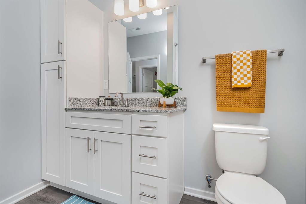 A bathroom with a white toilet and a yellow towel.