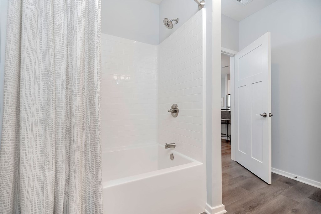 A white bathroom with a shower and a door.