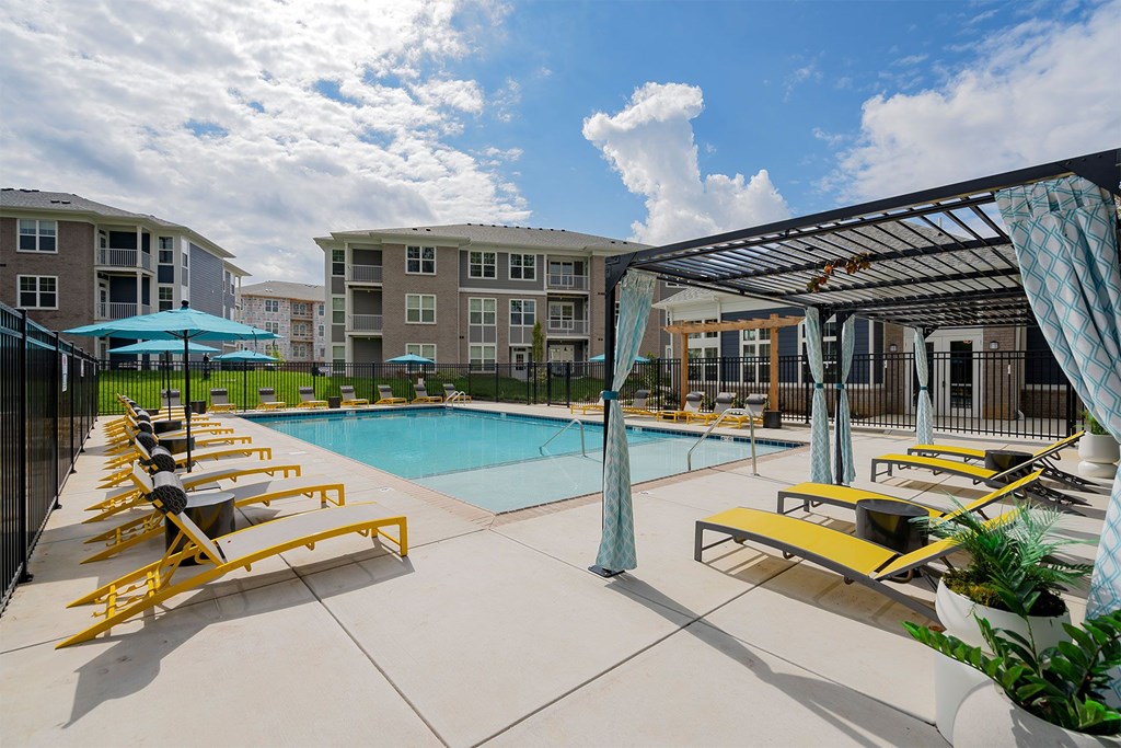 Jeffersonville, IN Luxury Apartments With In-Unit Washer And Dryer - The Laurel - Outdoor Swimming Pool with Poolside Loungers, Pergola, Fence, and Views of Apartment Buildings.