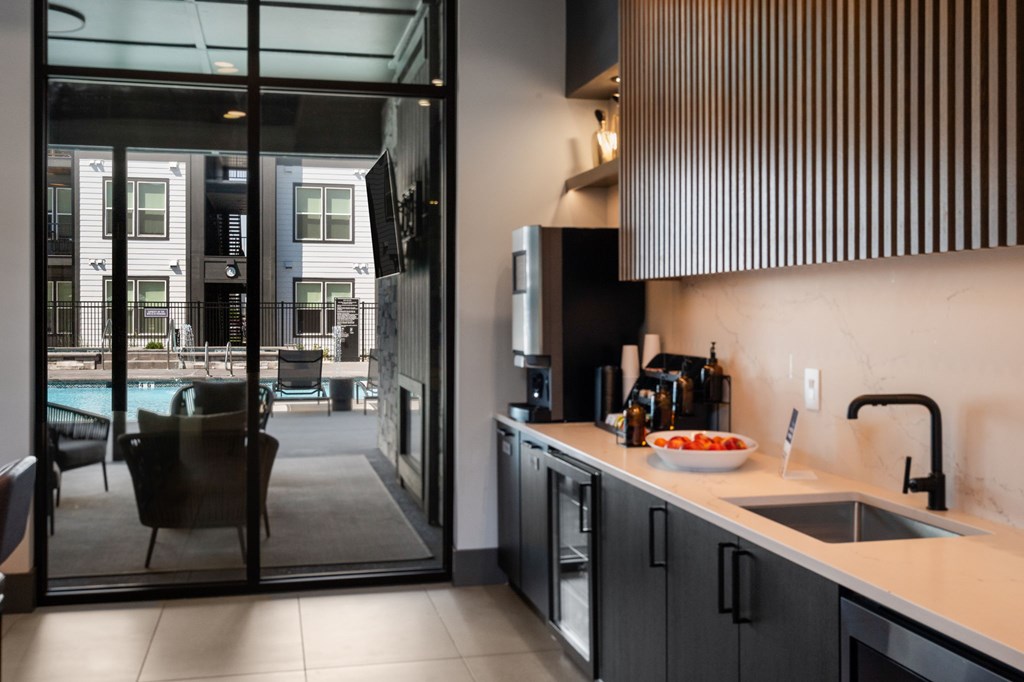 A modern kitchen with a view of a pool and apartment building.
