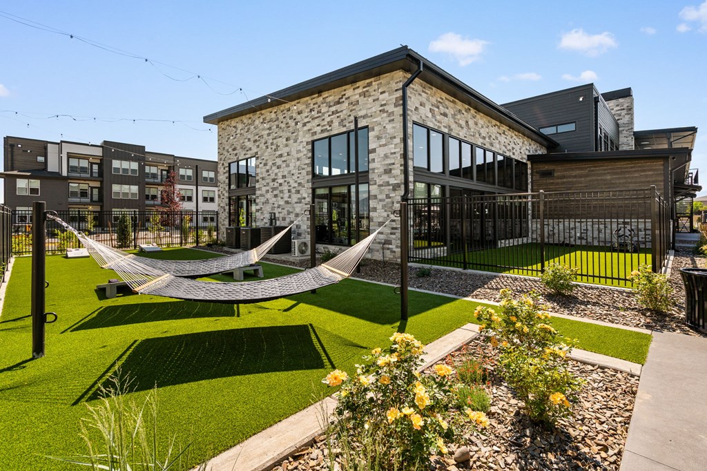 A hammock is strung between two poles in a backyard.
