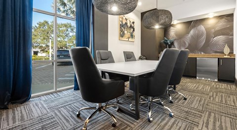 A conference room with a white table and black chairs.