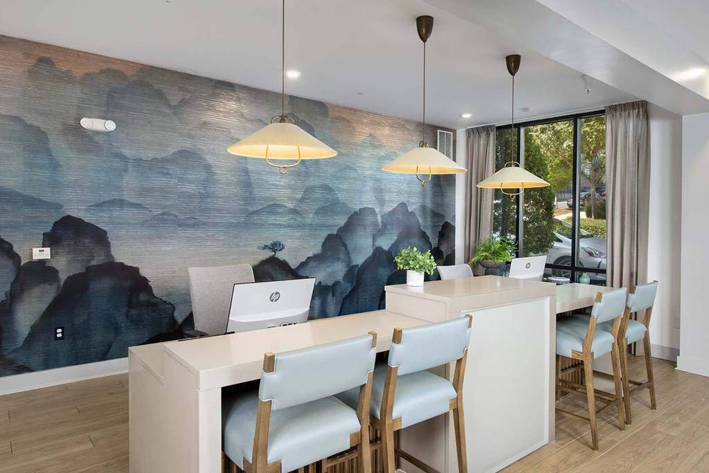 A room with a desk and chairs with a mountain mural on the wall.