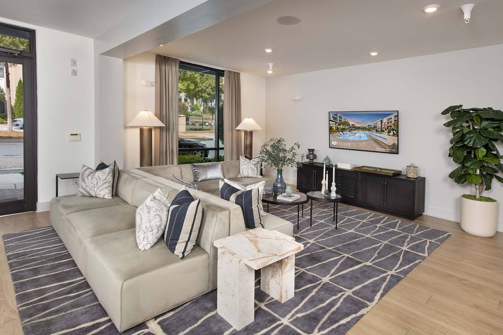 A living room with a large couch, a coffee table, and a painting on the wall.