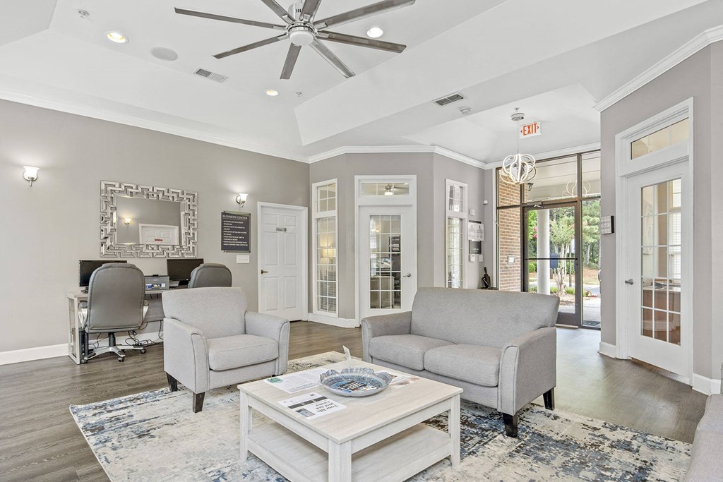 A living room with a white ceiling fan and grey couches.