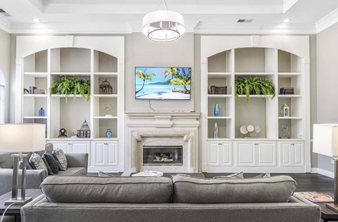 A living room with a grey couch and a fireplace.