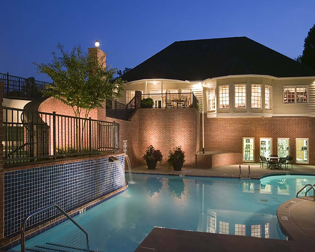 a swimming pool at night in front of a resort building